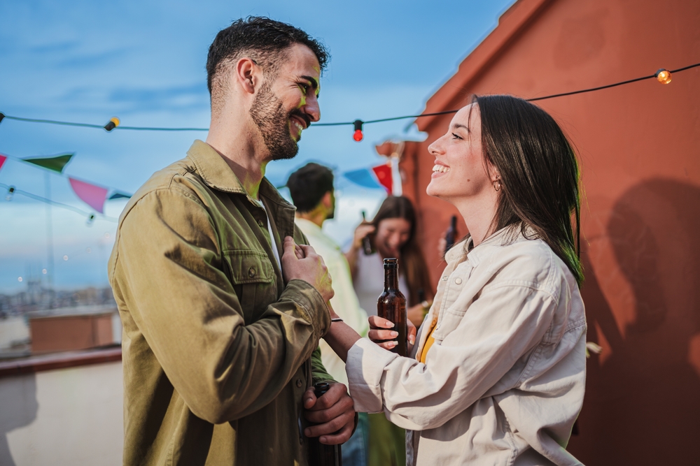 A smiling young couple touching each other and having fun at a rooftop