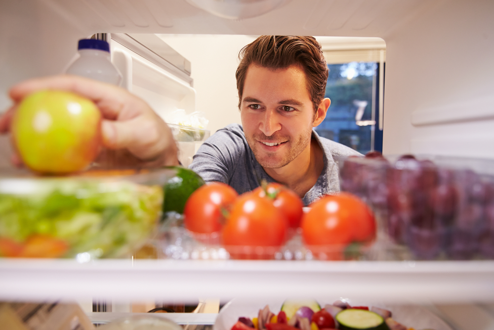 Man looking inside his refrigerator for a snack.