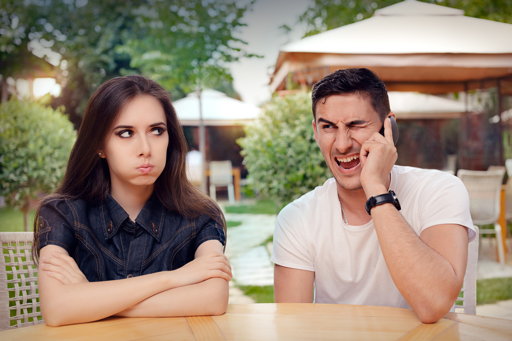 A girl feeling bored and angry while her boyfriend is on his phone
