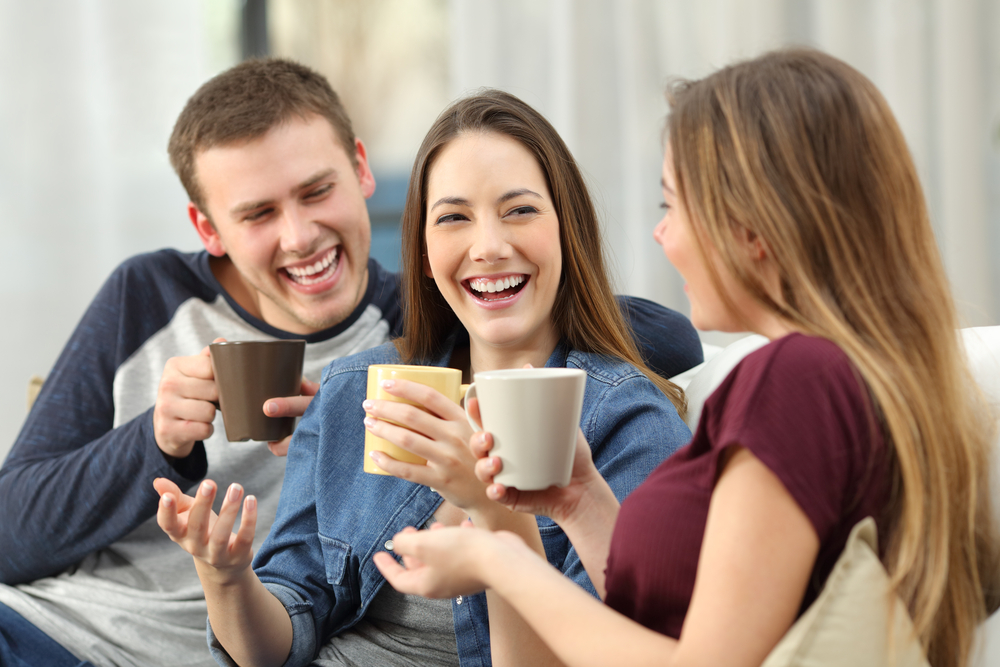 Three happy friends drinking coffee and having fun