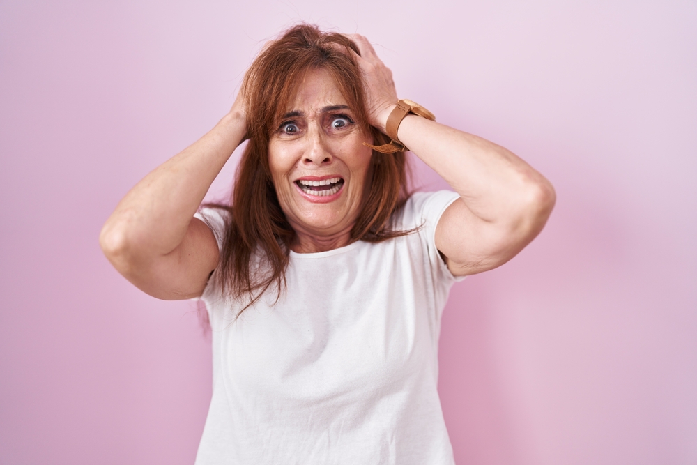 woman standing with hands on head scared and distressed