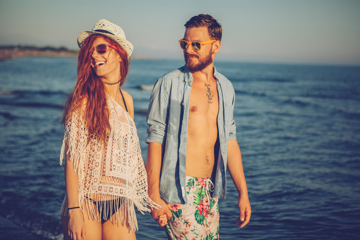 Young couple walking on the beach by the sea.