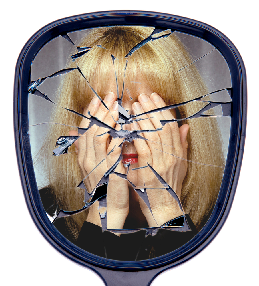 Woman looking into a cracked mirror.