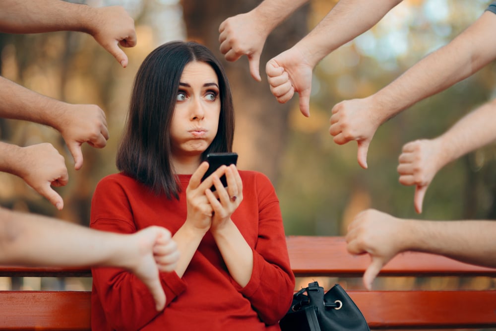 Woman getting the thumbs down from friends.