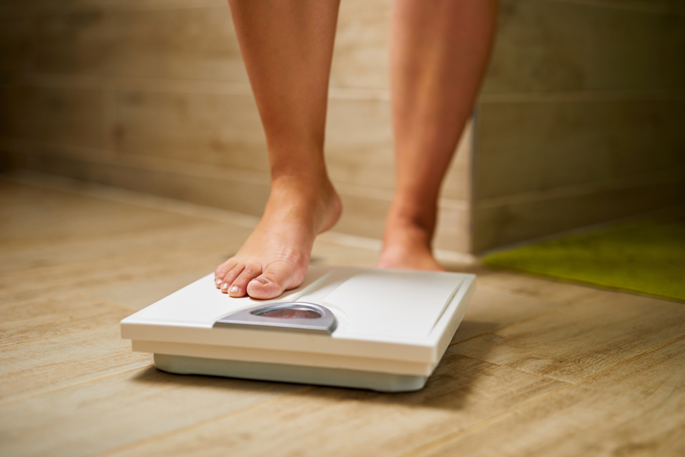Woman stepping on a scale to weigh herself.