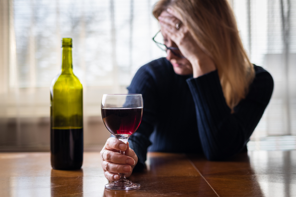A lonely sad woman drinking red wine alone