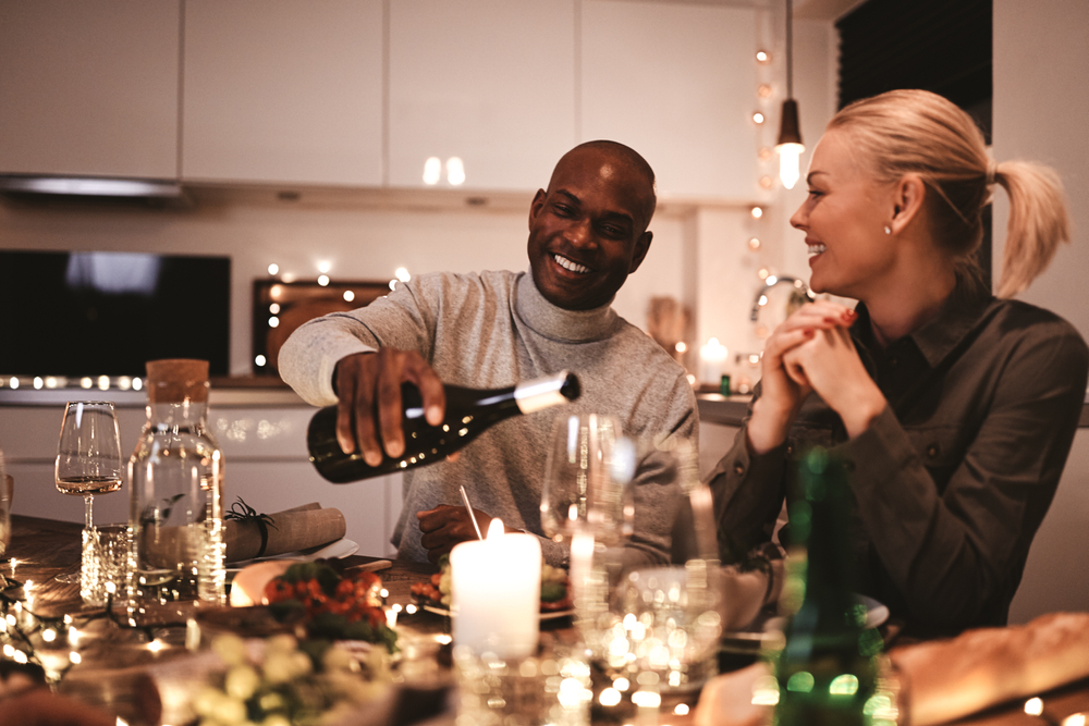 A mature man pouring his female friend a drink at dinner