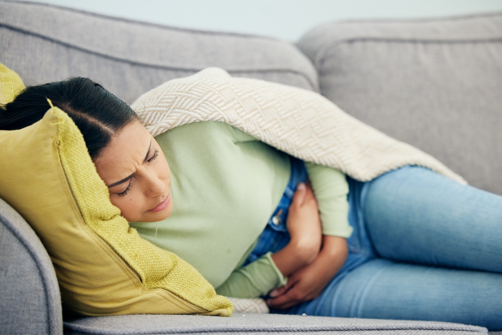 Woman laying down with a stomach ache.