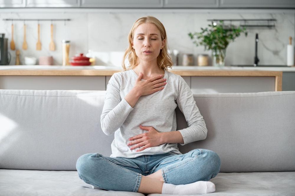 Woman with her hand on her heart breathing and meditating to improve her mental health. 