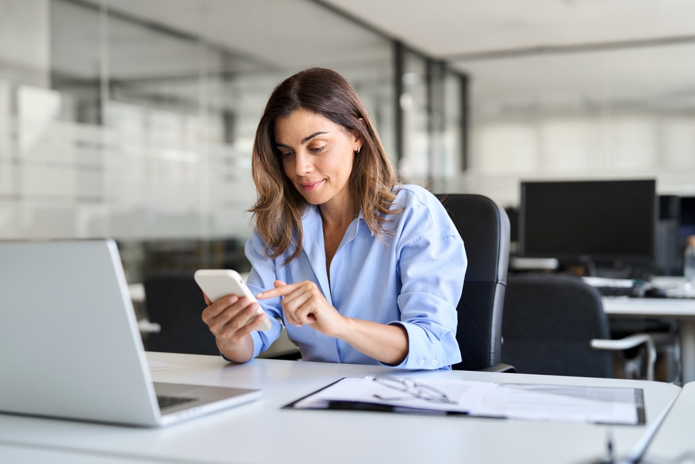 A busy professional middle age woman working on her laptop and phone