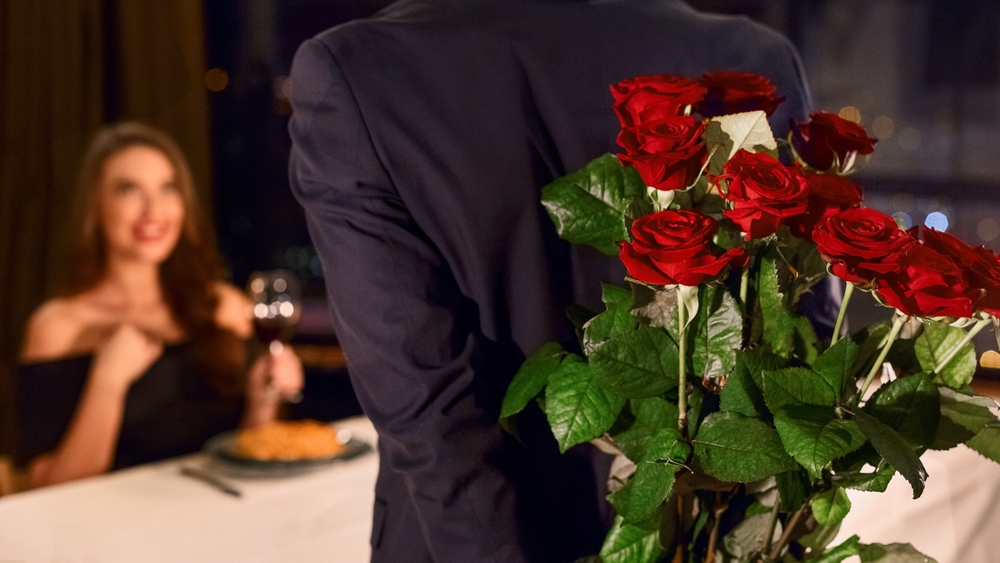 Man holding flowers behind his back as a gift for his girlfriend.