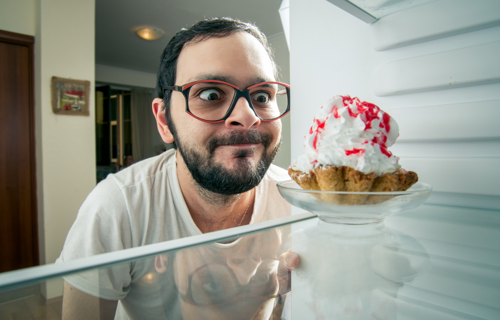 Funny man looking at dessert in his refrigerator.