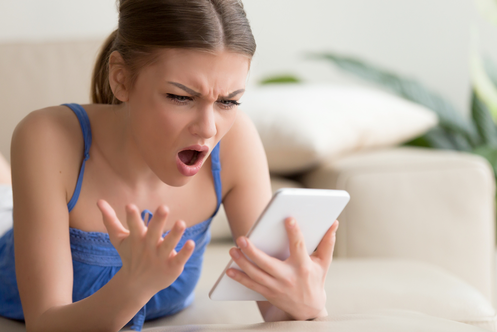 A young woman feeling shocked because of what she is seeing in her phone