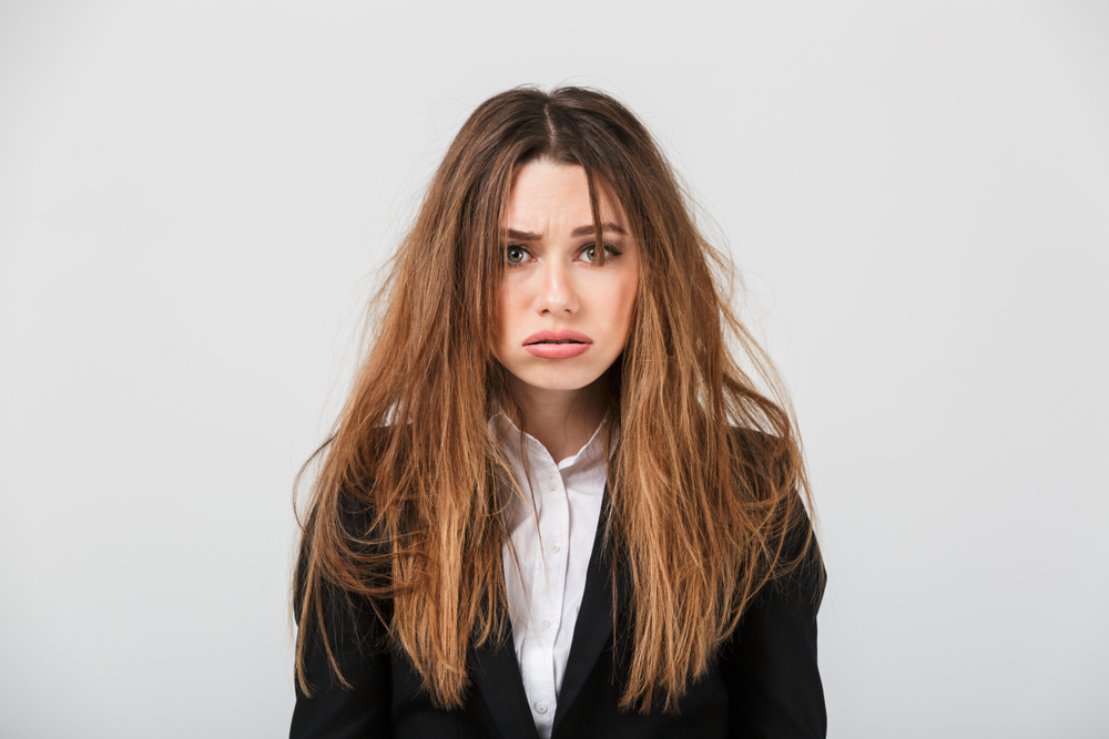 An exhausted businesswoman wearing a suit and her hair is messy