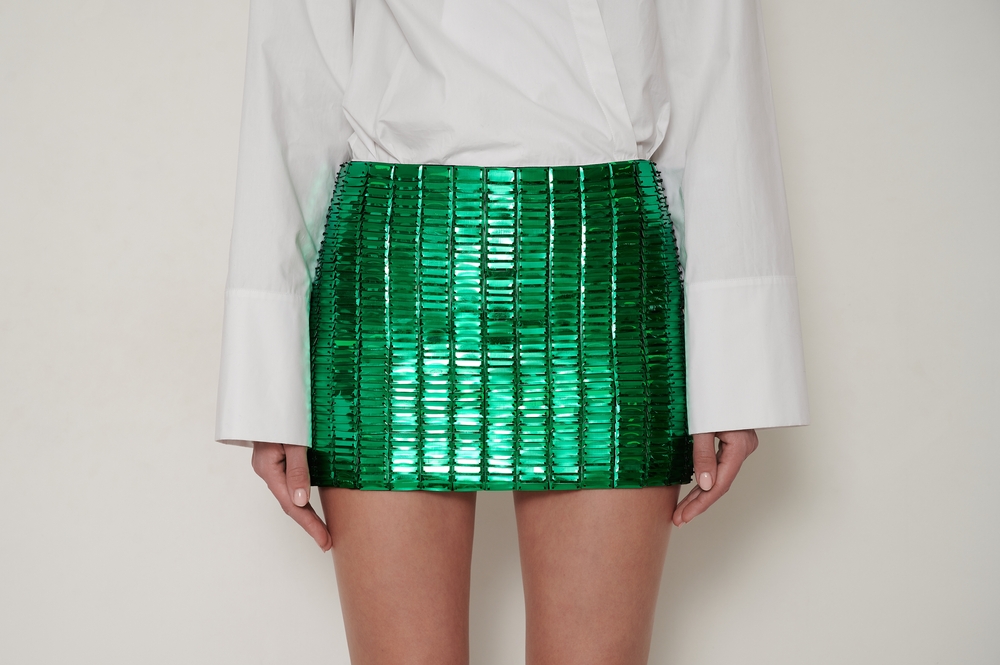 A lady wearing a neon green mini skirt and white shirt