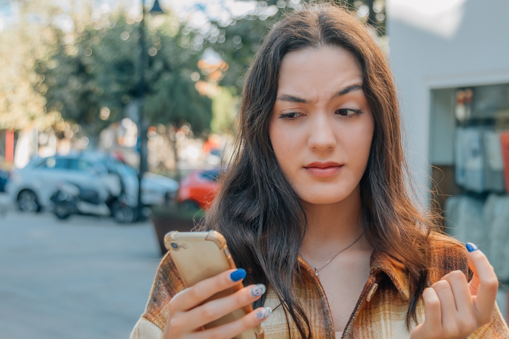 A woman looking suspiciously at her mobile phone.