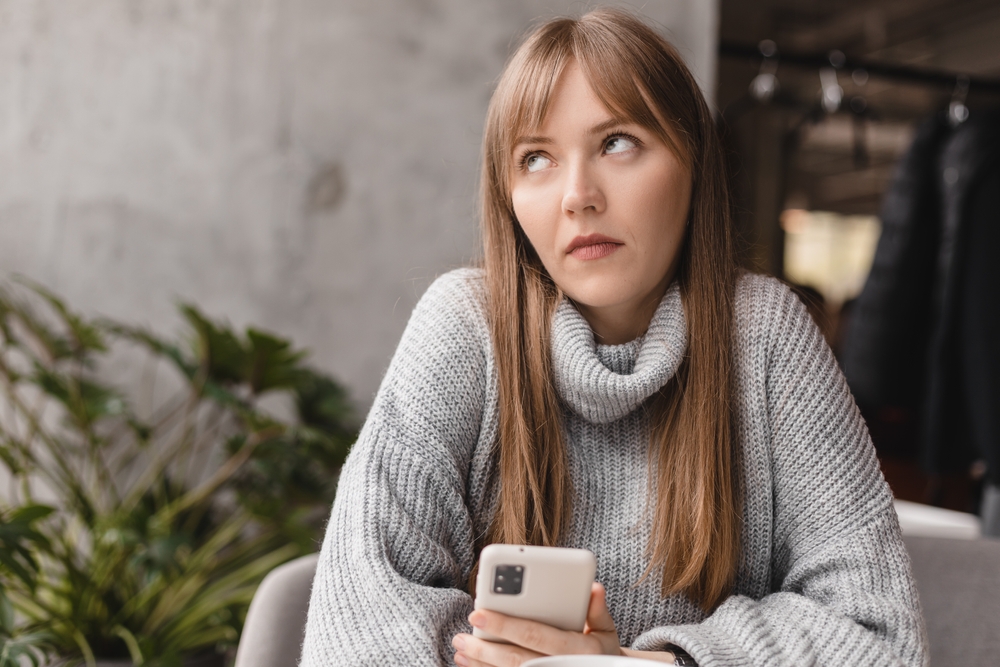 Confused woman looking bored or annoyed holding her phone