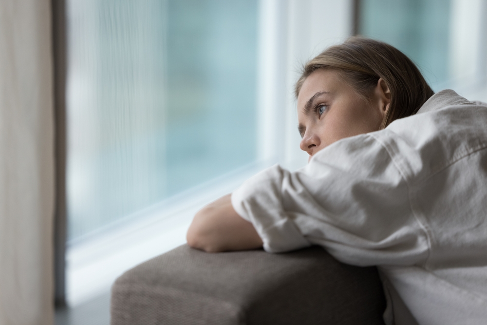 Woman looking out the window feeling alone. 