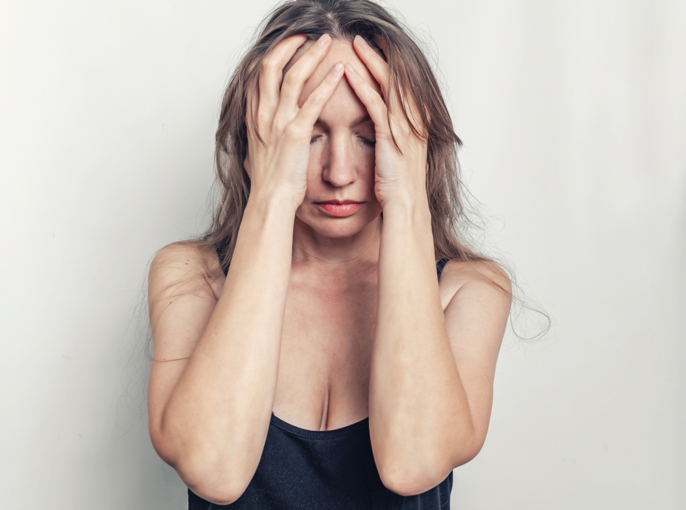 Woman covering her face looking worried or fearful
