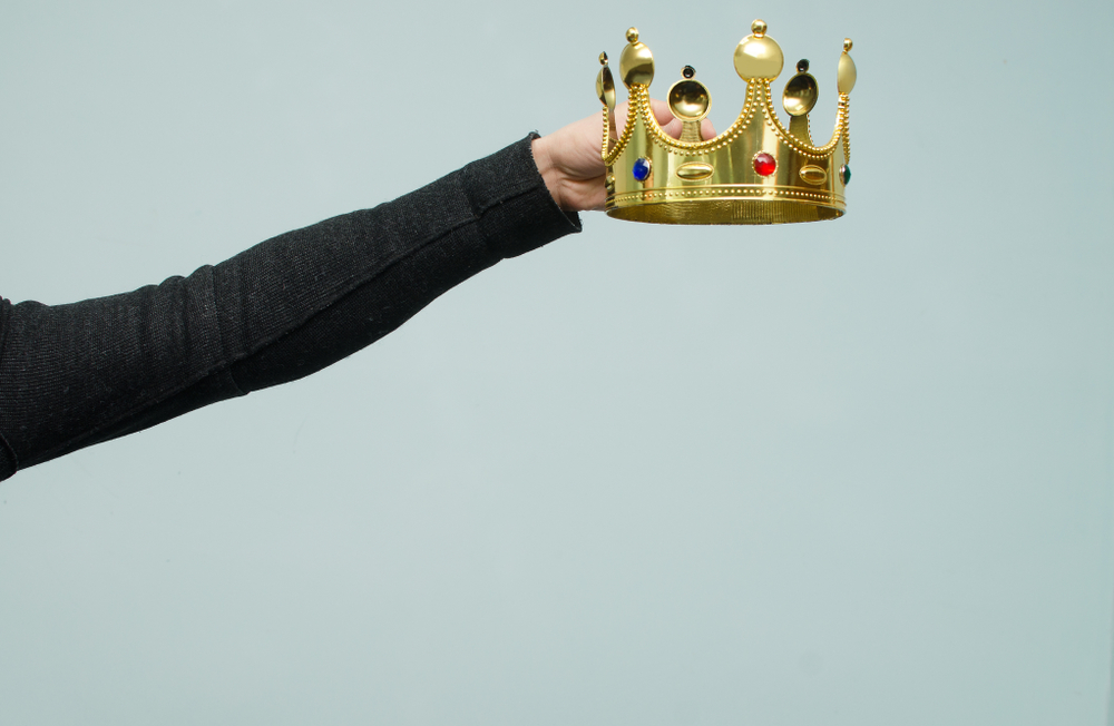 Hands holding a gold crown.