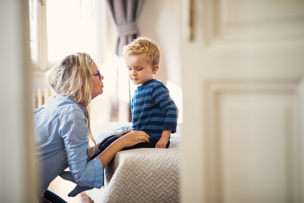 A young mother talking to her toddler son in the house