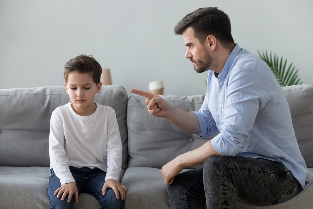 An angry father scolding his son and wagging his finger at him
