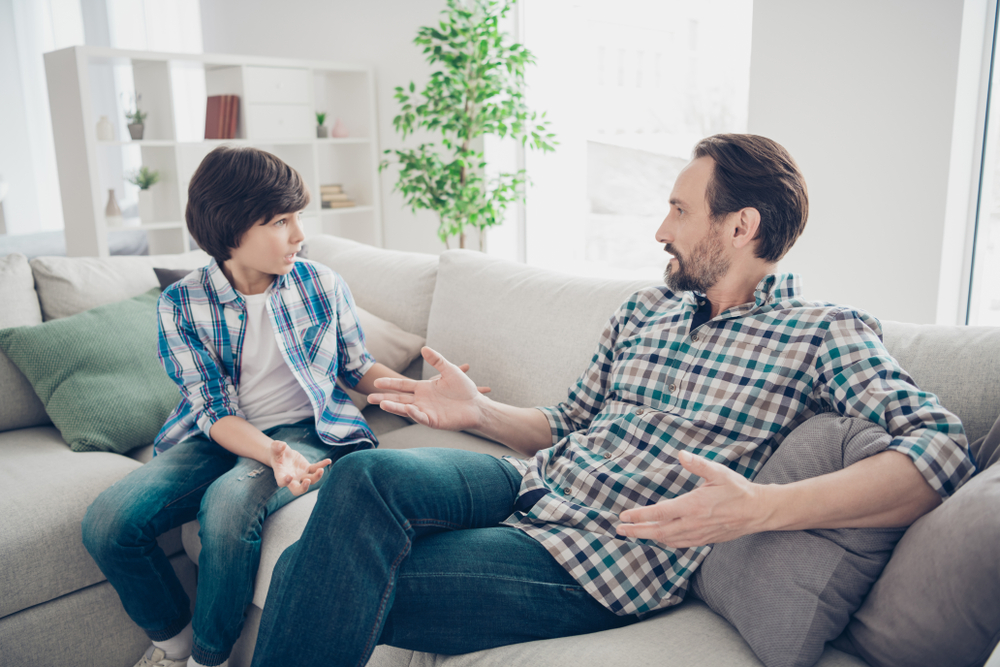A father and son having a serious conversation on the sofa.