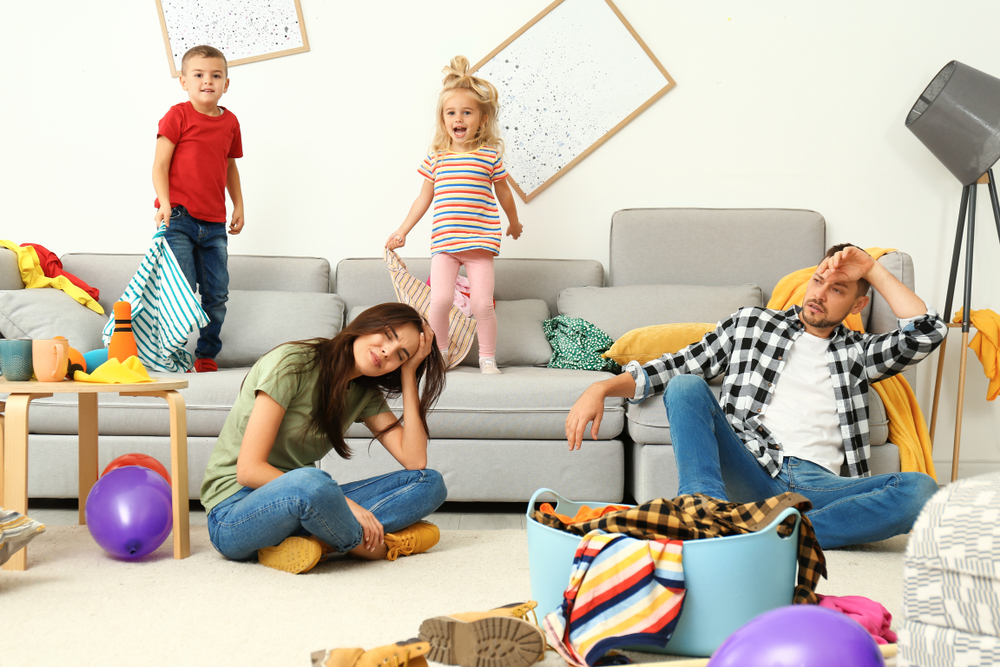 Frustrated parents and their mischievous children in their messy room