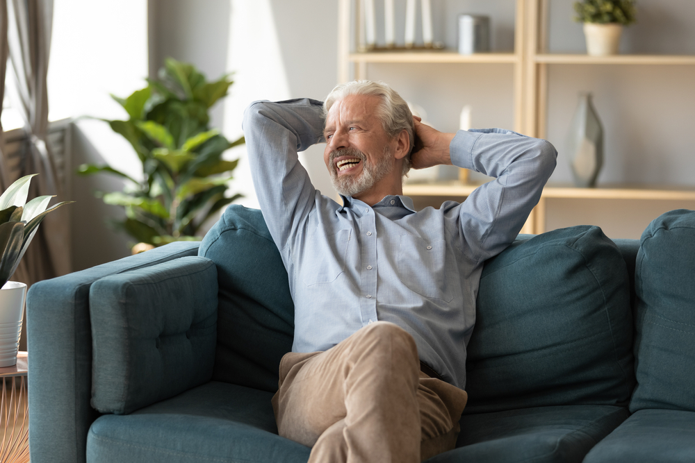 A happy smiling senior man relaxing on the couch in the living room