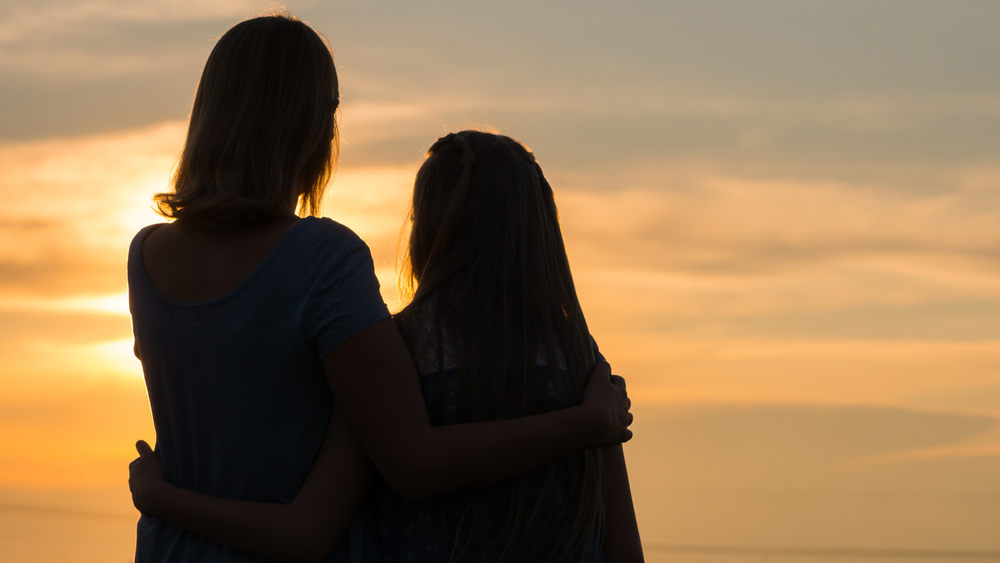 Silhouettes of mother and daughter at sunset.
