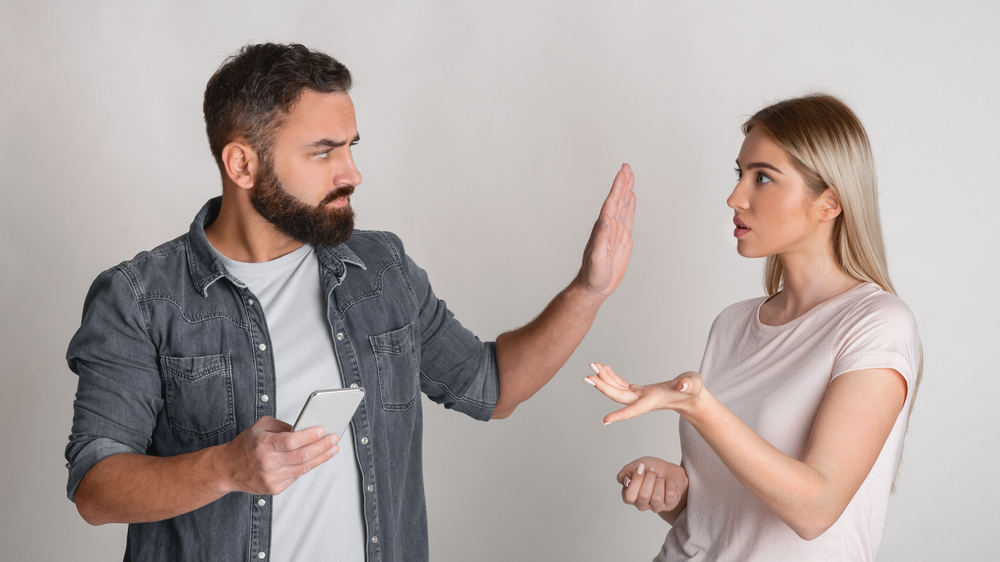 Couple fighting as one exerts control and jealousy.