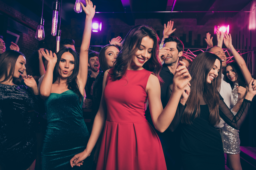 A woman wearing a bright red dress out dancing with friends.