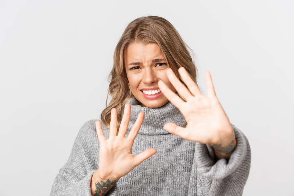 Woman looking annoyed, putting hands up to say no, set boundaries, reject something