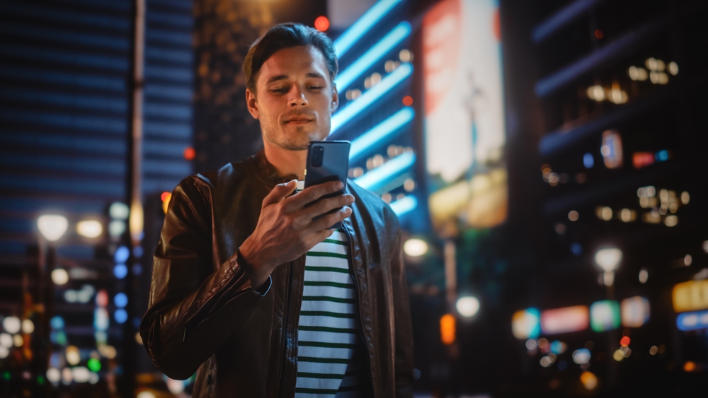 A young man using his smartphone and walking down the street