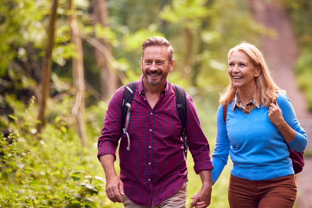 A happy muddle age mature couple holding hands in love and going on a hike
