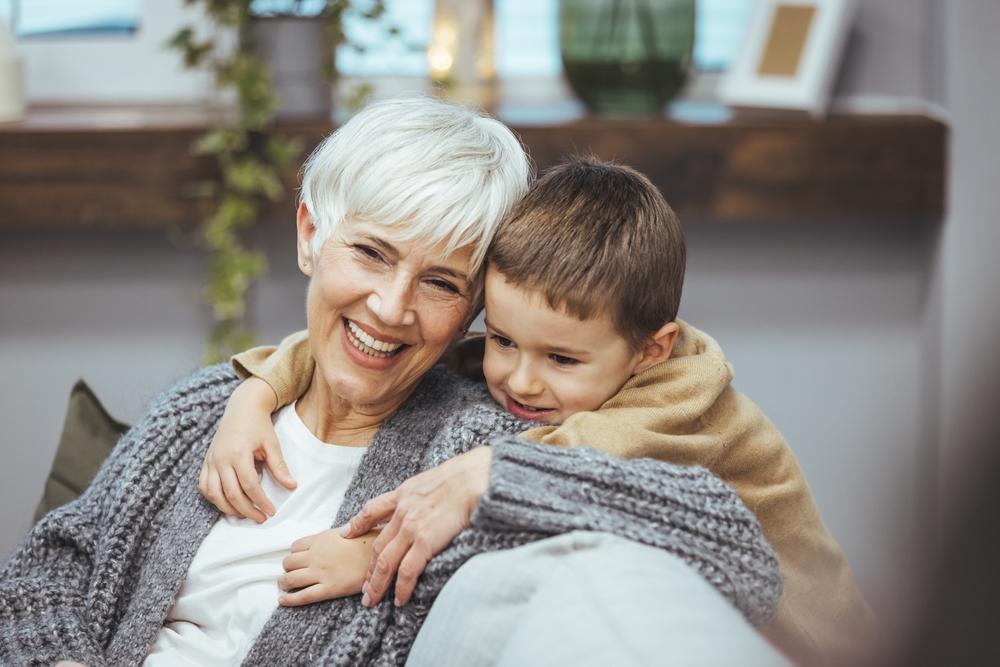 A smiling elderly grandmother playing with her grandson