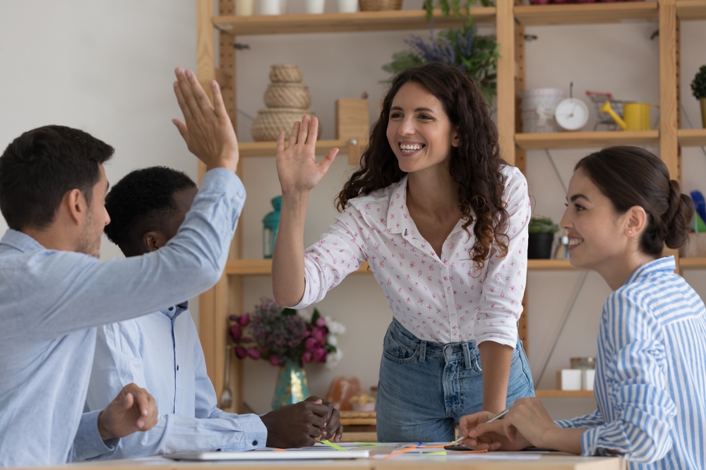 A woman celebrating with a man and about to give him a high five, happy colleagues