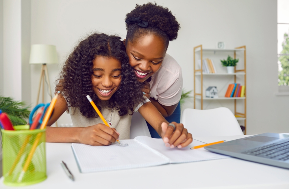 A happy black mother helping her daughter with her homework