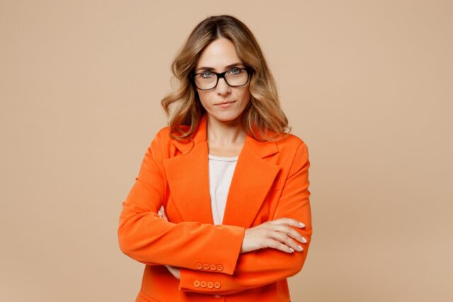 A young woman in an orange jacket looking serious