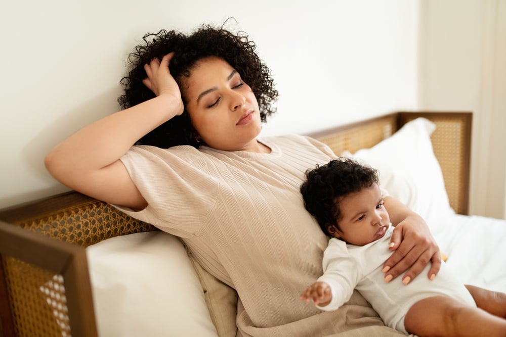 Sad tired mom with baby on her lap