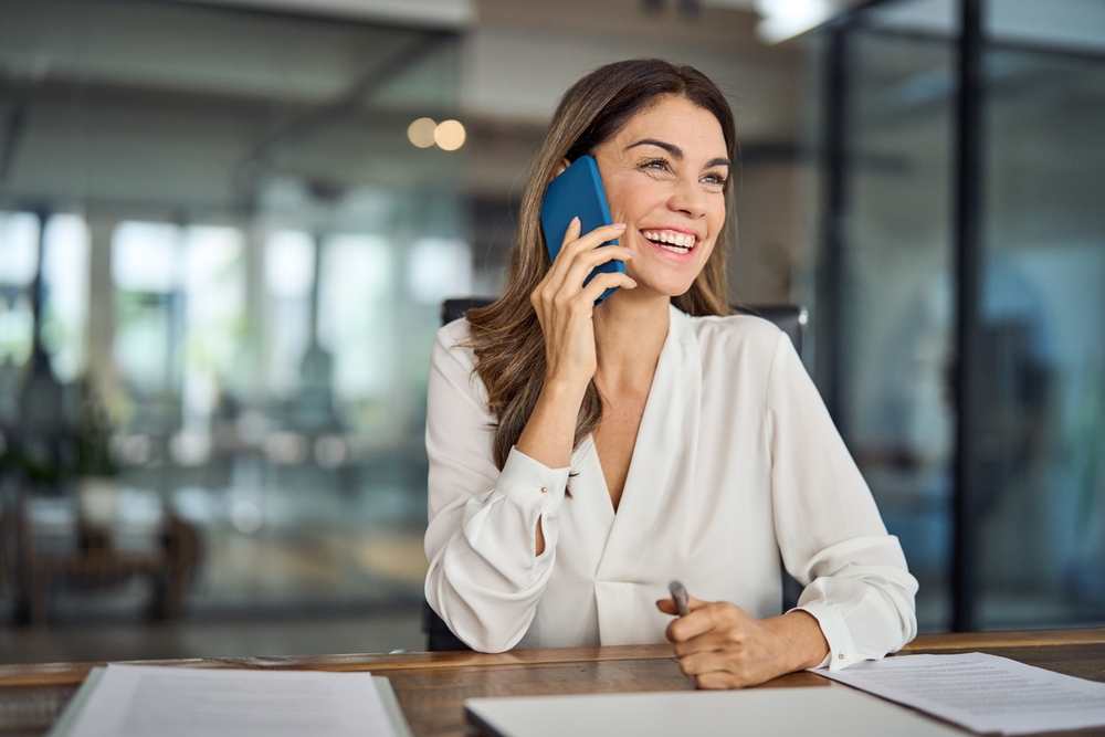 A happy, smiling, successful mature business woman at work taking a call