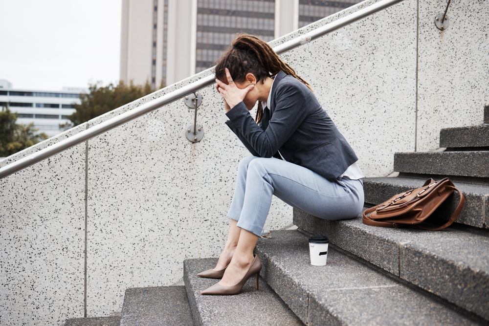 Sad business woman sitting on the stairs leading to her office