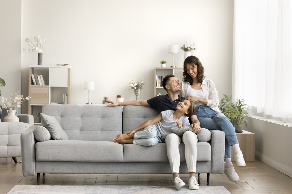 A happy family cuddled up on the couch, both parents and their girl child