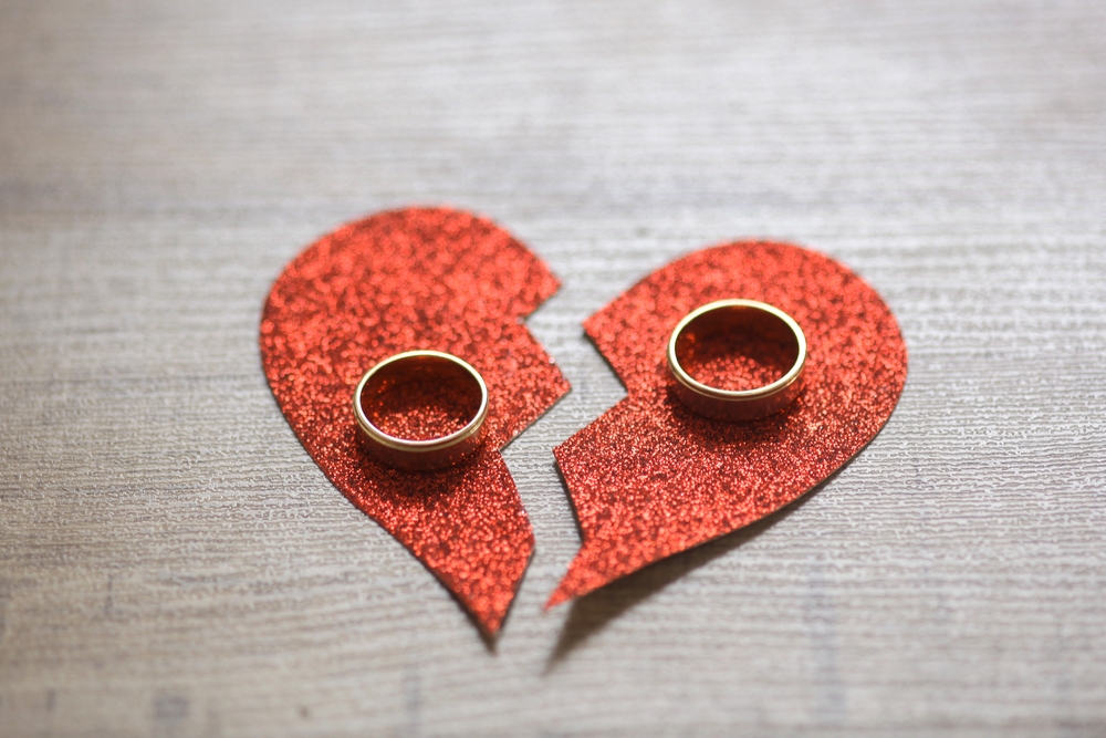 Divorce concept with wedding rings and a broken heart.