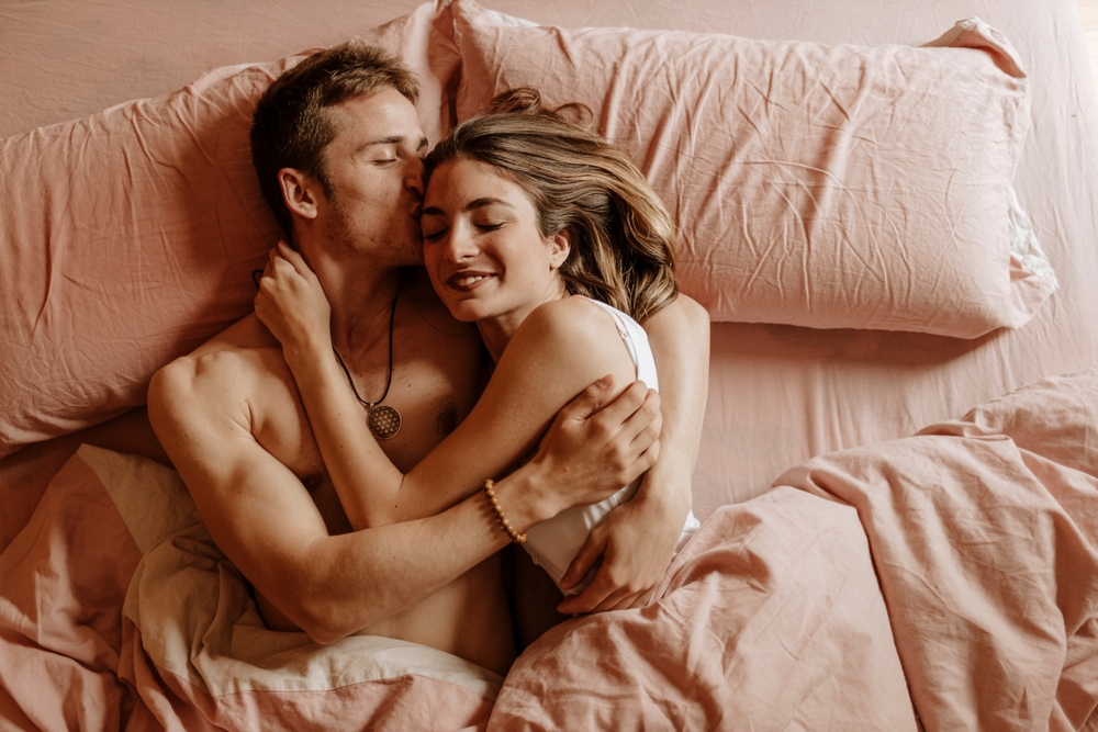 An affectionate young couple cuddling in bed and sleeping together