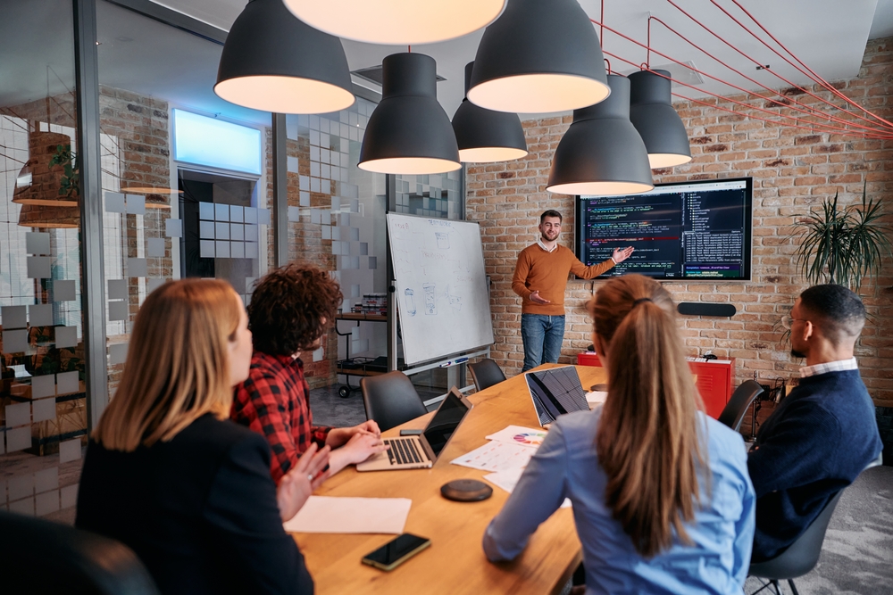 A business amn giving a presentation in front of his colleagues in a meeting