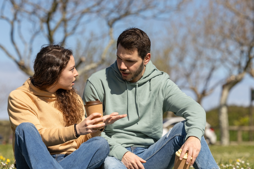A couple in a park talking with one listening