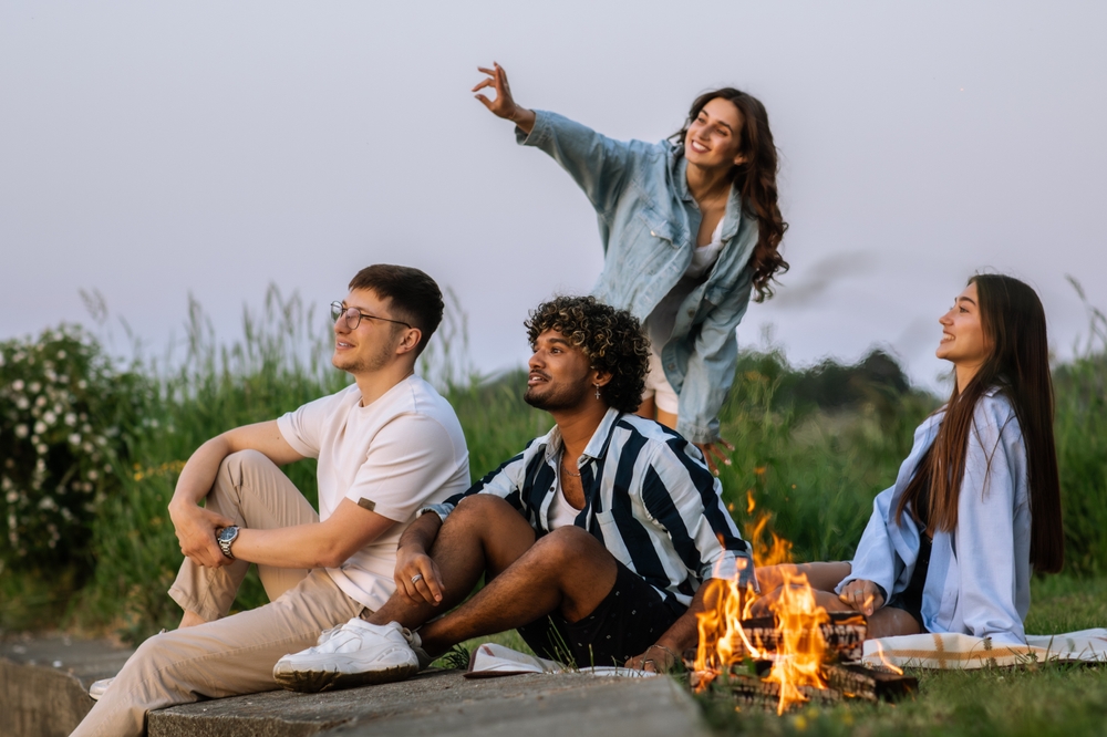 A happy group of friends sitting by a fire and talking