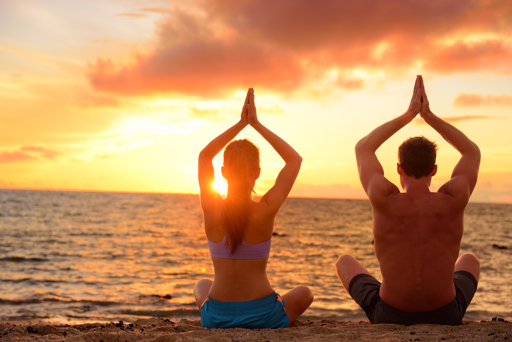 Couple doing yoga on the beach