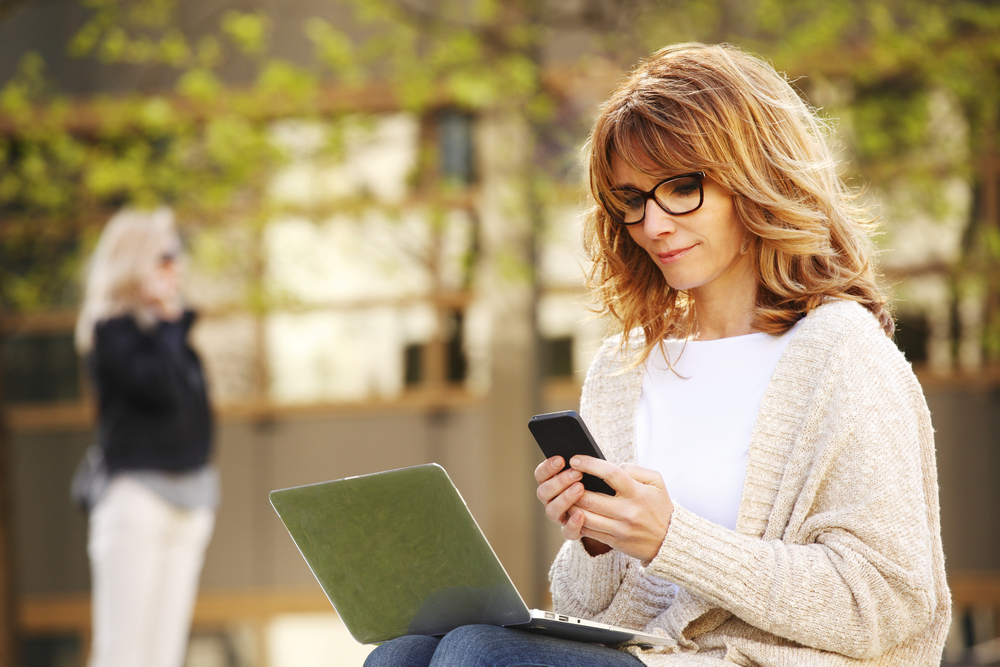 A busy young sales woman working with her phone and laptop